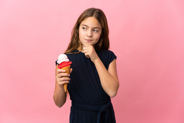 Child with a cornet ice cream over isolated pink background and looking up