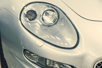 close-up halogen headlight of white retro car. car in the garage