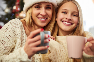 Smiling woman with daughter drinking tea on New Year Eve