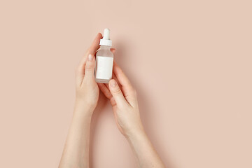a bottle of serum in hand on a beige background