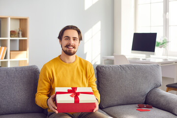 Cheerful bearded man on webcam shows his girlfriend a gift he prepared for her in honor of her...