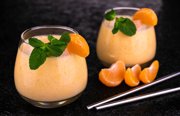 
Two glasses with tangerine mint smoothies on a black background.