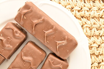 Close-up of four chocolate bars on a white plate on a straw mat.