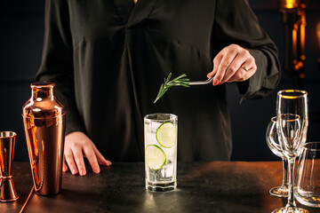 Woman on making fresh gin tonic cocktail with lime slices