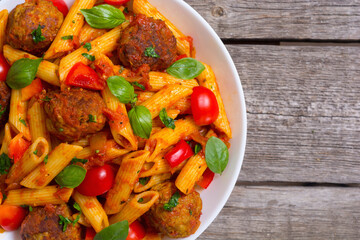 Italian penne pasta with meatballs and tomatoes