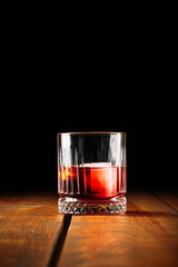 Side view on negroni cocktail in old fashioned glass on the wooden table