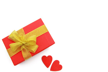 Red gift box tied with a gold bow and 2 red wooden hearts on a white background. Concept for Happy Women, Mother's Day, Valentine's Day, Greeting card design. The view from the top. Flat. Copyspace.