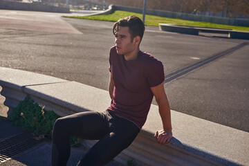 Young man leaning on a low wall