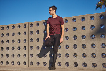 Man dressed in sweats stands against a wall