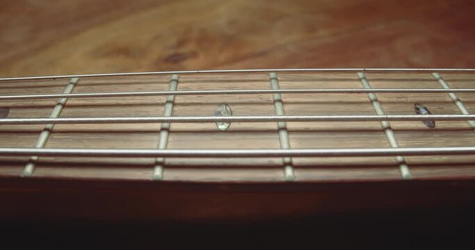 Gentle slider along bass guitar strings following neck