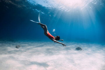 Woman with fins and air bubble underwater in ocean.