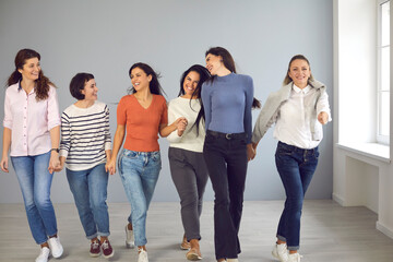 Obraz premium Always ready to support each other. Group of happy confident smiling young women in their 20s and 30s walking together and holding hands. Concept of success, female solidarity and mutual understanding