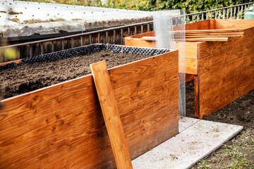 A raised bed made of wood planks is built in the garden