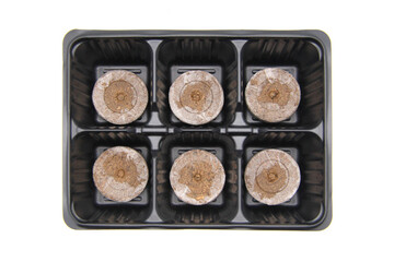 New empty plastic pots in the form of cells and compressed soil for seedlings on a white background. The concept of landscaping the house, growing plants and vegetables on the windowsill. Top view. 