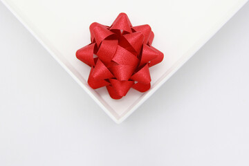 Beautiful, red, festive bow in a white box on a white background. Attention symbols concept for happy women, Mother's Day, Valentine's Day, Greeting card design.The view from the top.Flatley.Copyspace