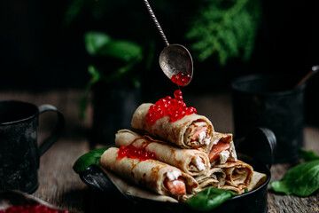 pancakes with red caviar fish and cream cheese on a wooden background