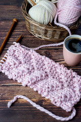 pink and white knitting yarn with knitting needles and morning coffee