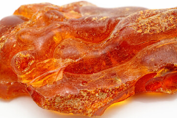 Macro piece of unique transparent yellow amber on a white background. A semi-precious stone made from petrified resin. Material for jewelry and ornaments. Copal. Sun stone. Fossil resin. Baltic gem.