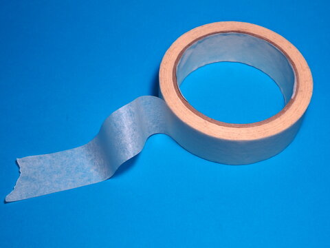 White adhesive paper tape on a blue background. Painter accessories.
 