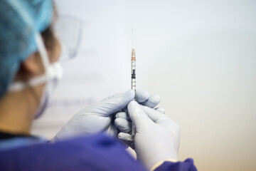 Shallow depth of field (selective focus) image with details of Covid- 19 vaccine administration in...