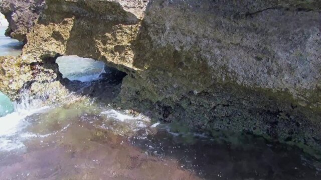 A natural opening in the indented rock on the beach.