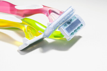 
Set of three multi-colored female razors for shaving isolated on white background. Pink, green and yellow. Flat lay, top view