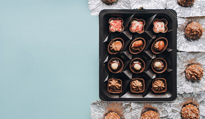 Close-up view of box of chocolates with foil wrapper, view from above. Blue background.