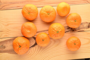 Several organic yellow tangerines, close-up, on a wooden table.