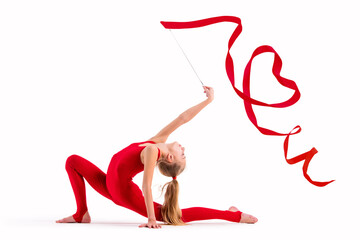 Girl gymnast in red overalls does exercise with a ribbon on white background, the ribbon curled...