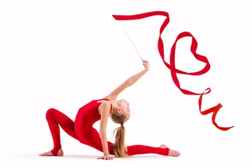 Foto op Canvas Girl gymnast in red overalls does exercise with a ribbon on white background, the ribbon curled into a heart, isolate © Maria Moroz