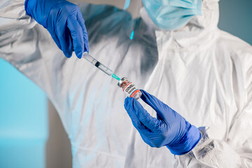 Close-up of Scientist hands in surgical gloves holding Covid-19 vaccine bottle and a syringe in a research medical lab or hospital. Draws medicine from the vial. Vaccination coronavirus campaign. 