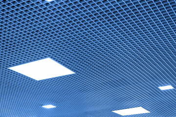 Mesh suspended ceiling with fluorescent or LED square lights in a modern shopping center or office building