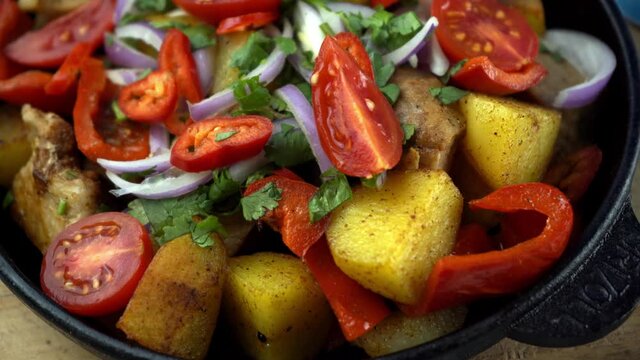Cooked food in a frying pan. Meat with tomatoes, red pepper, onion, parsley and potatoes. Pork ojakhuri with vegetables. Georgian cuisine. Home menu. Modern Kitchen.
