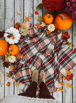 Overhead view of woman's feet on plaid scarf surrounded by fall items.