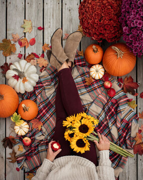 Overhead view of woman's legs and torso surrounded by fall items.