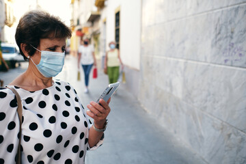 old lady looking at her cell phone and women walking after their pals
