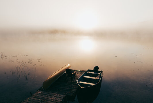 Empty dock with boats tied up on a foggy morning on a calm lake. - Powered by Adobe