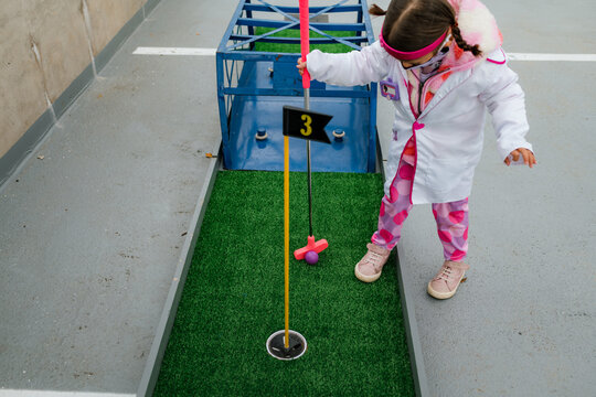 preschool girl in doctor costume playing mini golf on halloween