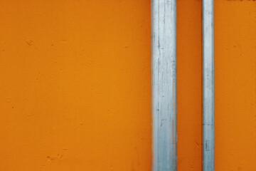 metal tubes in front of orange wall