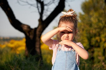 little girl protects herself from the sun with her hands