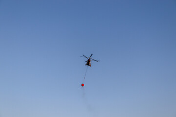 helicopter fly over the sky and extinguishes a fire
