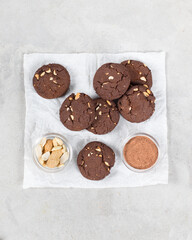 Vegan dessert cacao cookies with whole peanuts on paper on a light gray background top view