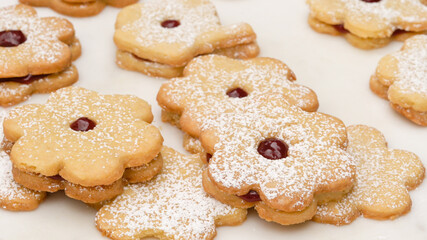 Flower shaped shortbread cookies filled with raspberry jam. Fresh baked cookies close up on white background