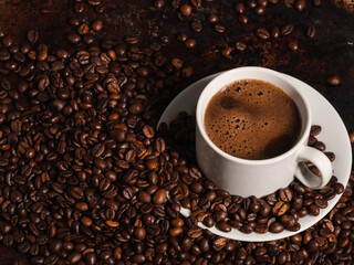 Close-up of a white espresso cup on a table with lots of coffee beans
