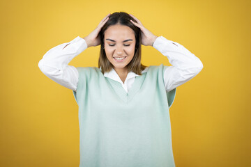 Fototapeta na wymiar Pretty young woman standing over yellow background suffering from headache desperate and stressed because pain and migraine with her hands on head