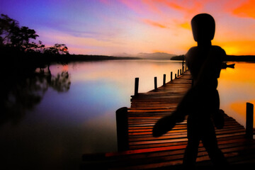 Un bonhomme en bois au bord de l'eau regardant le coucher de soleil