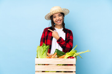 Young farmer Woman holding fresh vegetables in a wooden basket pointing to the side to present a product