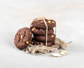 Vegan cacao cookies with peanuts, tied with jute thread on a linen napkin on a light gray background in rustic style