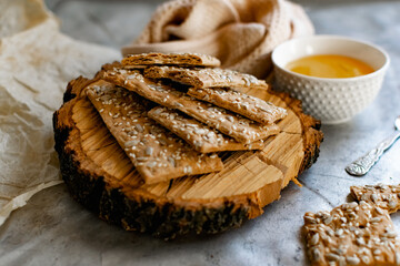 Healthy and nutritious diet bread with sesame and sunflower seeds on a thin crunchy malt base. Near natural bee honey and a wooden stand sawn