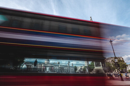 Red Double Decker busses passing the Trafalgar Square in front of the Nelson column